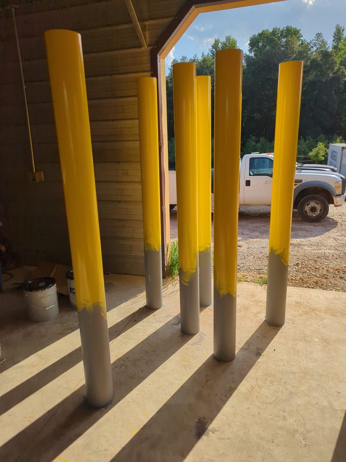 Steel pipe bollards finished in safety yellow standing on a shop floor