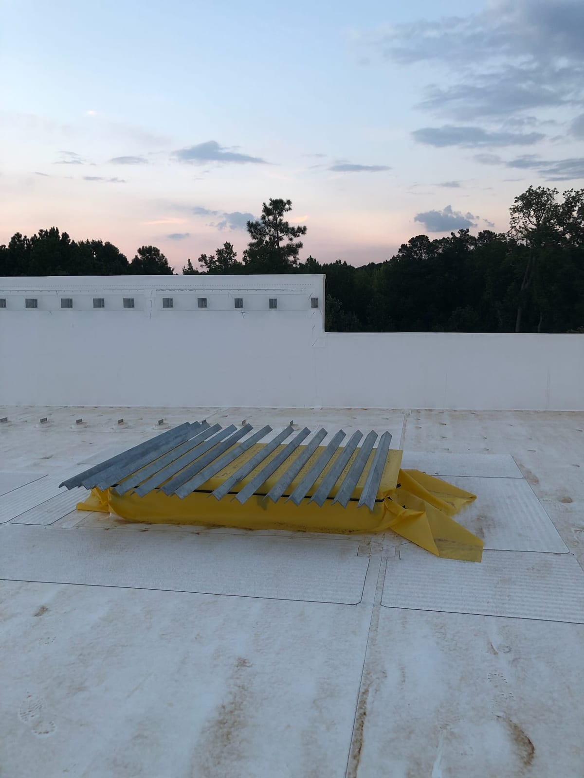 Bundle of galvanized steel angle kickers on a white roof at dusk